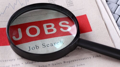 Lupe mit Zeitung, die das Wort "Job Search" hervorhebt