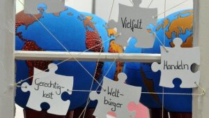 Objekte der Ausstellung "Globales Lernen" an der FSU, zwei Globen und die Worte "Vielfalt", "Handeln", "Weltbürger" und "Gerechtigkeit" auf Karten