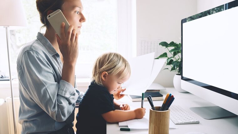 Frau im Homeoffice, die arbeitet und ein Kind betreut