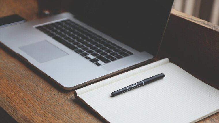 Laptop mit Stift und Papierblock