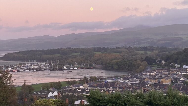 view of Bangor, the Irish Sea, and Eryri with pink clouds and moon