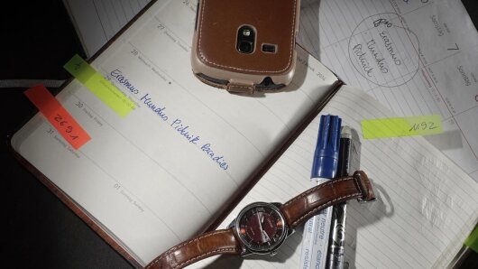 aufgeschlagener Terminkalender mit Uhr und Handy