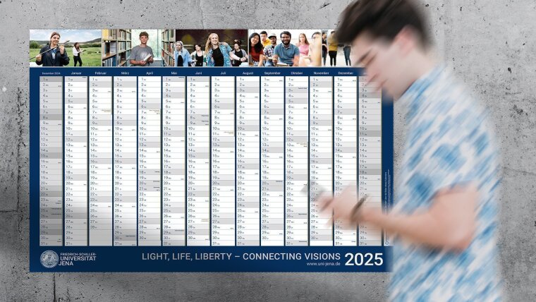 Junger Mann geht am Wandkalender 2025 der Universität vorbei.