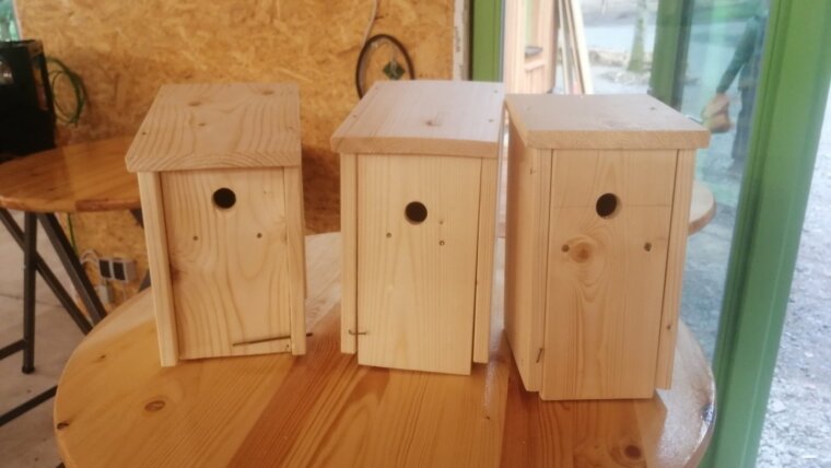 Three of the completed nesting boxes stand next to each other on a wooden table.