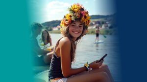 Mädchen sitzt an einem Fluss und hat einen Blumenschmuck auf dem Kopf.