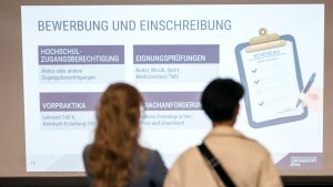 Zwei STudierende informieren sich zur Bewerbung und Einschreibung an der Uni Jena