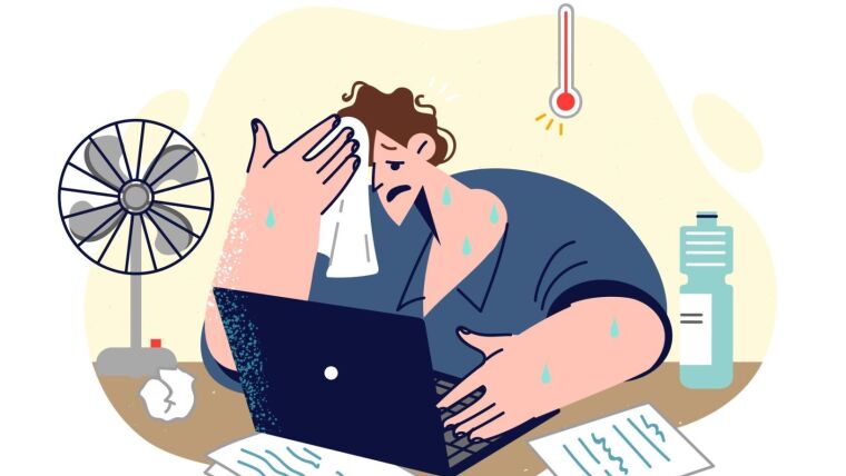 Schwitzender Mann am Laptop mit Ventilator und Thermometer im Hintergrund