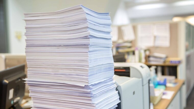 Papierstapel in einem Büro mit Drucker