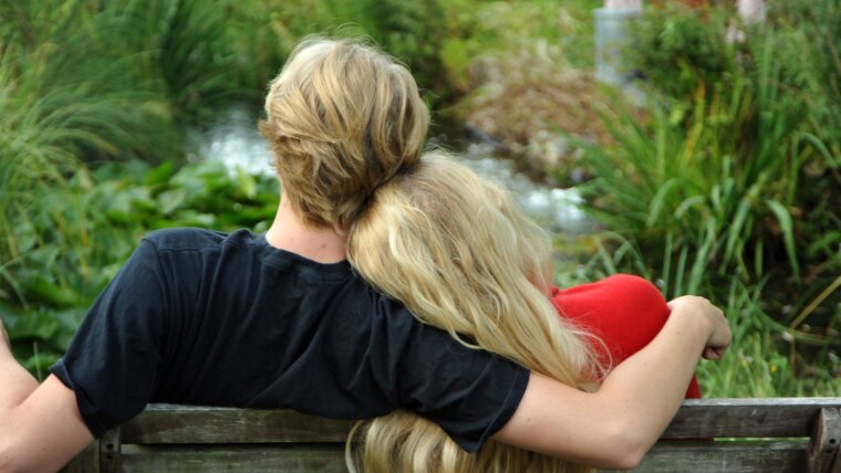 A young couple sitting on a bench.