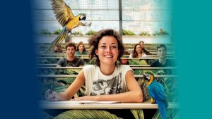 Person sitzt in einem Hörsaal; um die Person fliegen paradiesische Vögel