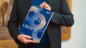 Universitätspräsident Prof. Dr. Andreas Marx hält ein Exemplar des Exzellenzantrags in der Hand