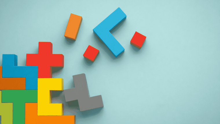 Bunte Holzbausteine in Puzzleform liegen auf hellem Hintergrund und symbolisieren das Zusammenspiel digitaler Kompetenzen.