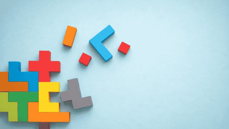 Bunte Holzbausteine in Puzzleform liegen auf hellem Hintergrund und symbolisieren das Zusammenspiel digitaler Kompetenzen.