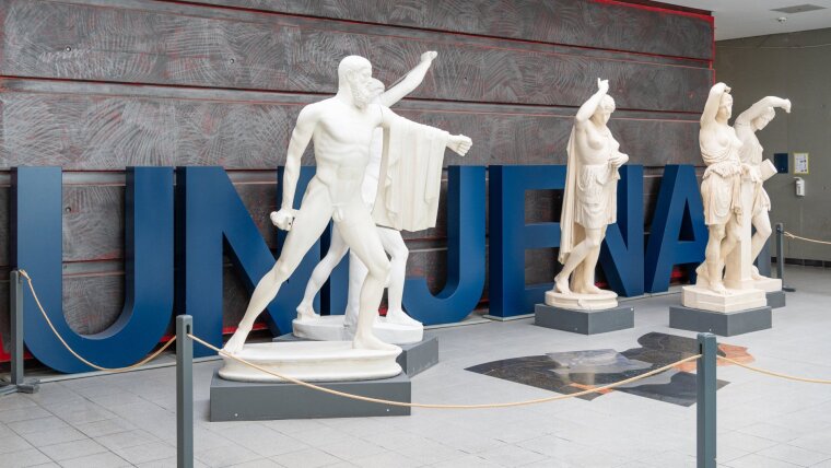 antike Statuen und der Uni Jena Schriftzug im Foyer am Campus
