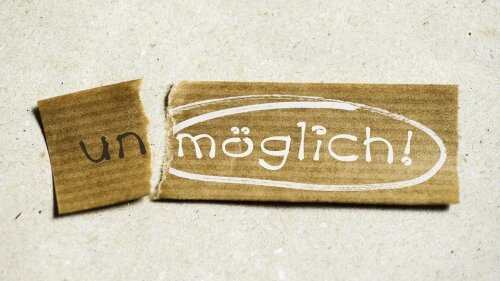 Pappzettel in zwei Teile zerrissen, sodass "(un-)möglich" zu lesen ist