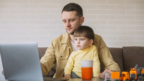 Sohn sitzt beim Vater, während er von zu Hause aus arbeitet