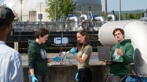 Nachwuchsforschende analysieren eine Wasserprobe vor einem der Wasserbecken in der Zentralen Kläranlage in Jena-Zwätzen.