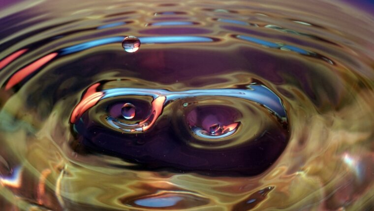 Tropfen fallen auf eine Wasseroberfläche.