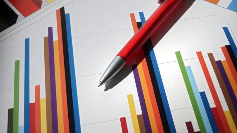 A red pen lies on a sheet of paper showing a multicoloured bar chart.
