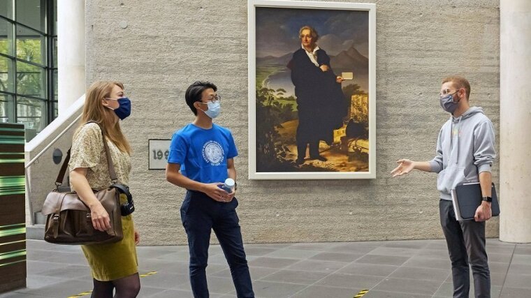 Three students with face masks in the library