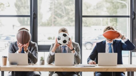 Drei Männer halten jeweils einen anderen Sportball