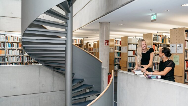 Studentinnen unterhalten sich in der Bibliothek