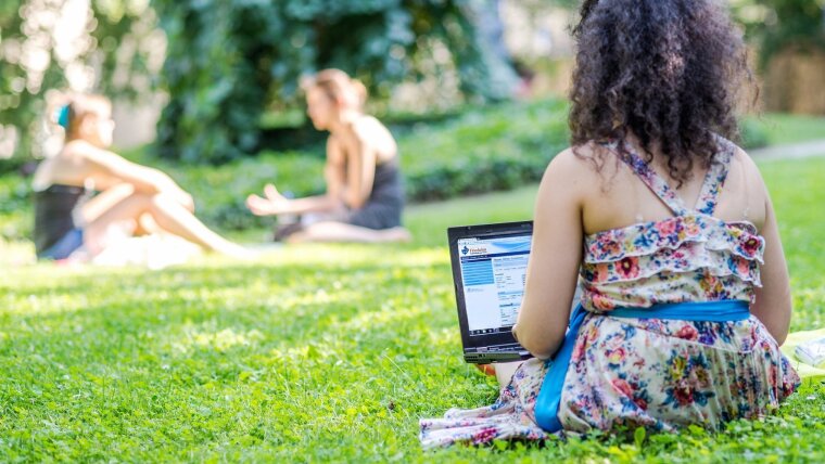 Studentin mit Laptop im Grünen