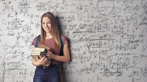 Studentin steht vor einem Whiteboard mit mathematischen Formeln