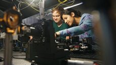 A young woman and a young man develop photonic nano-films on optical equipment