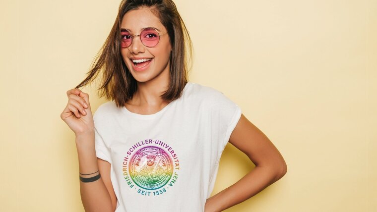 Junge Frau, die lachend ein T-Shirt mit »Siegel«-Motiv in Fakultätsfarben trägt