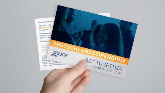 Hand hält Postkarten des Deutschlandstipendiums