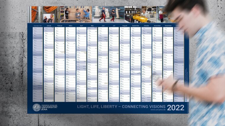 Junger Mann geht am Wandkalender 2022 der Universität vorbei.