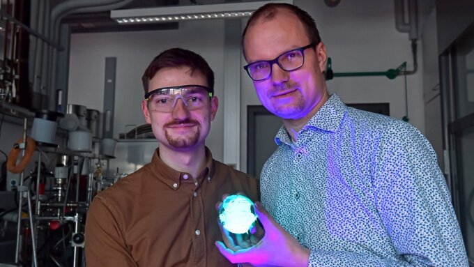 Flavio Portwich (links) und Jun.-Prof. Dr. Robert Kretschmer mit einem fluoreszierenden Polymervlies.