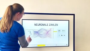 Dr. Bettina Färber zeigt die Funktionen eines Exponats der Ausstellung zur künstlichen Intelligenz.