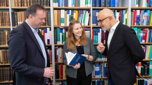 Die Professoren Adrian Schmidt-Recla (r.) und Achim Seifert mit der Doktorandin Zara Luisa Gries.