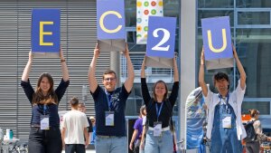 Studierende halten Würfel mit dem Aufdruck E C 2 U in die Höhe.