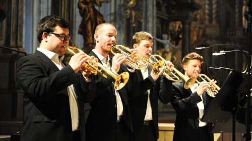 Four brass players in a church.