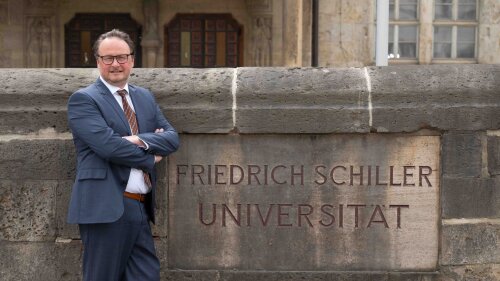 Prof Dr Andreas Marx stands next to the sign: Friedrich Schiller University Jena.