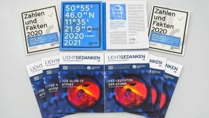 Several issues of the Annual Report 2020/2021 and LICHTGEDANKEN 09 lying on a table.