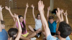 Kinder sitzen zusammen mit Sportlehrer.
