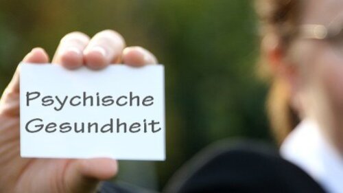 Frau im Hintergrund hält Visitenkarte zu Psychischer Gesundheit