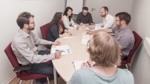 Mehrere Personen sitzen an einem Tisch während eines Teammeetings