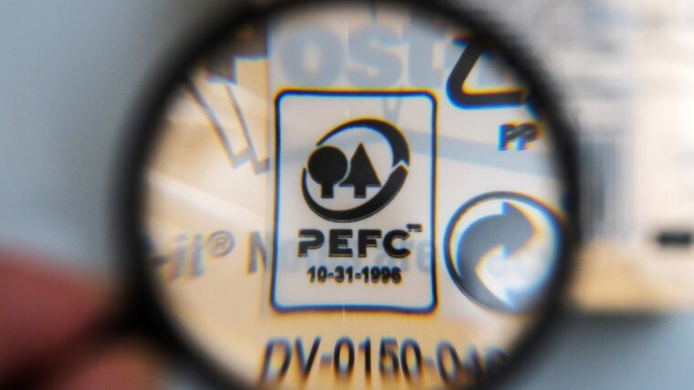 Das PEFC Logo für nachhaltige Fortwirtschaft. Es wurde durch eine Lupe fotografiert.