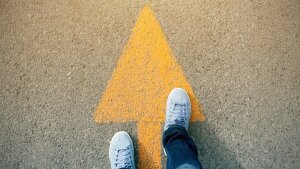 Feet standing on an arrow pointing forward