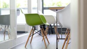 Several white and one green chair at a table