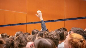 Person raises hand in a crowded lecture hall