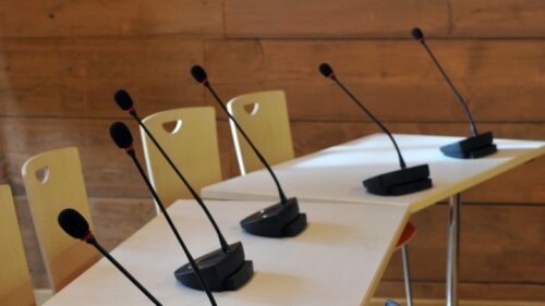 Symbolbild zeigt Mikrofone, Tische und Stühle