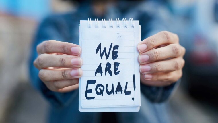 Person holding a notepad reading ‘We are equal—wir sind gleich’