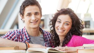 Female and male student looking at a book in the library