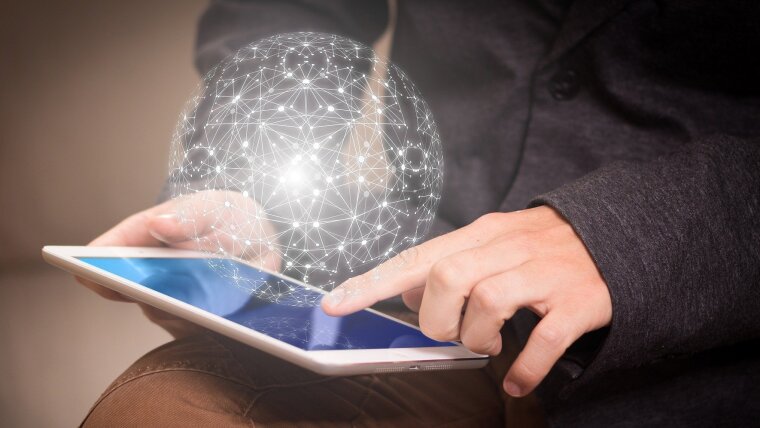 A person types on a tablet from which a spherical net emerges.